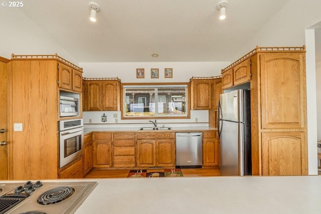 461 Terrace Dr, Rockaway Beach, OR 97136 - kitchen with stainless steel appliances, a sink, brown cabinetry, light countertops, and vaulted ceiling