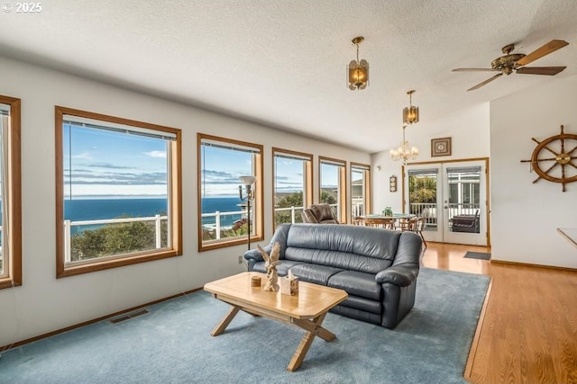 461 Terrace Dr, Rockaway Beach, OR 97136 - living area with a chandelier, a ceiling fan, a textured ceiling, baseboards, and a water view
