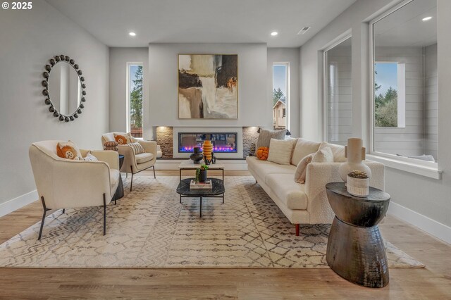 living room featuring wood finished floors, baseboards, a glass covered fireplace, and recessed lighting