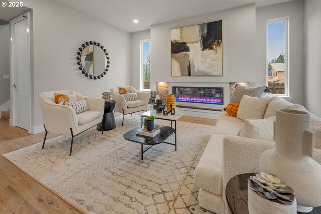 living room with wood finished floors, recessed lighting, a glass covered fireplace, and baseboards
