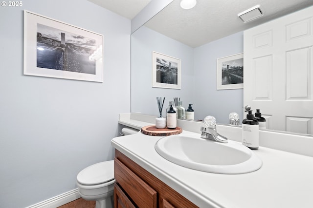 bathroom featuring vanity, toilet, and a textured ceiling