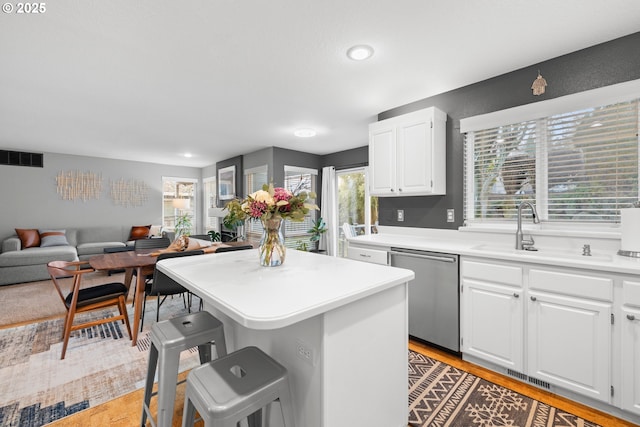 kitchen featuring white cabinetry, stainless steel dishwasher, a kitchen breakfast bar, and a kitchen island