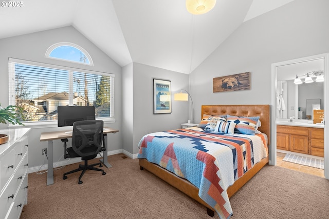 bedroom with vaulted ceiling, light colored carpet, and ensuite bathroom