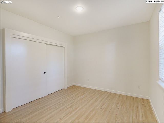 unfurnished bedroom with multiple windows, light hardwood / wood-style flooring, and a closet