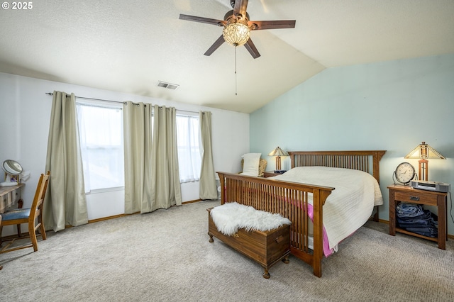 carpeted bedroom featuring vaulted ceiling, a textured ceiling, visible vents, and a ceiling fan