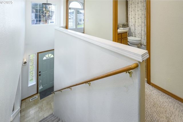 foyer entrance with a chandelier, visible vents, and baseboards