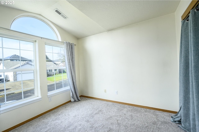 carpeted empty room with lofted ceiling, baseboards, visible vents, and a textured ceiling