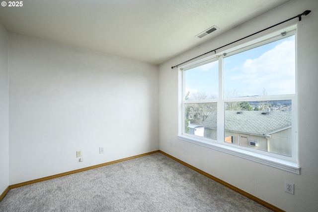 carpeted empty room with visible vents and baseboards