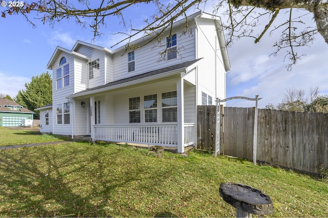 traditional home featuring covered porch, fence, and a front yard