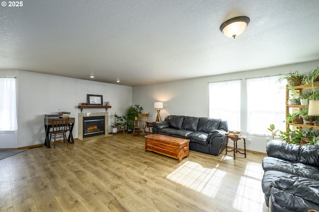 living area with a textured ceiling, light wood finished floors, a fireplace with flush hearth, and baseboards