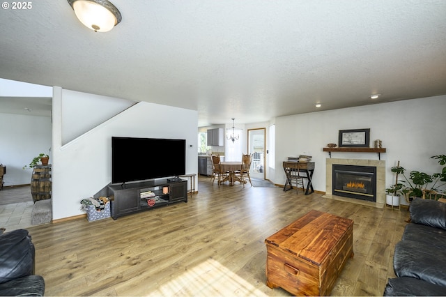 living area with a textured ceiling, baseboards, a fireplace, and wood finished floors