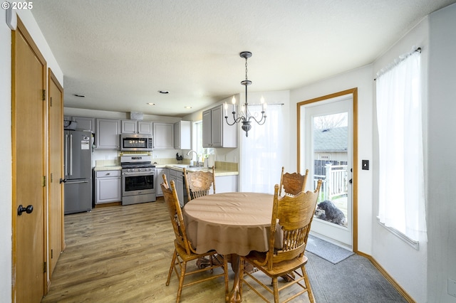 dining space with baseboards, a textured ceiling, light wood-type flooring, a chandelier, and recessed lighting