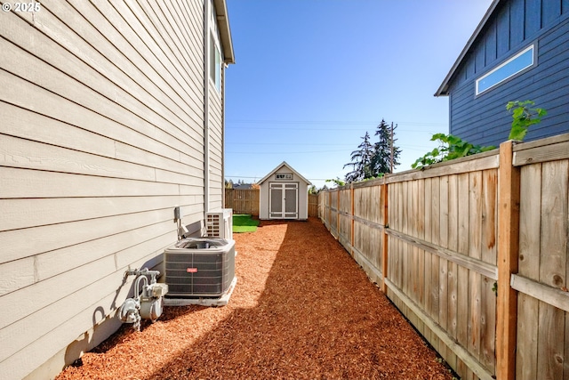 view of yard featuring central air condition unit, a fenced backyard, an outbuilding, and a shed