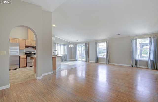 15807 NE 48th Cir, Vancouver, WA 98682 - unfurnished living room with vaulted ceiling, a chandelier, light wood-style floors, and arched walkways