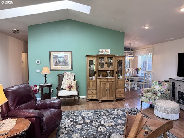 living room featuring visible vents, recessed lighting, lofted ceiling with skylight, and hardwood / wood-style floors