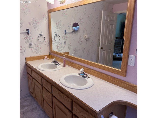 bathroom featuring a sink, wallpapered walls, and double vanity