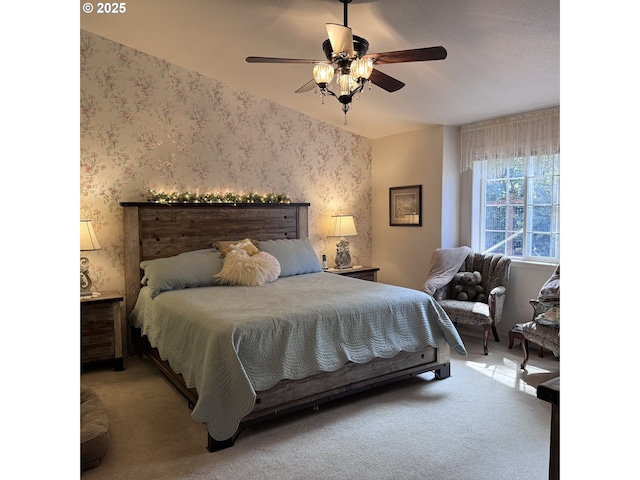 bedroom with a ceiling fan, wallpapered walls, and light carpet