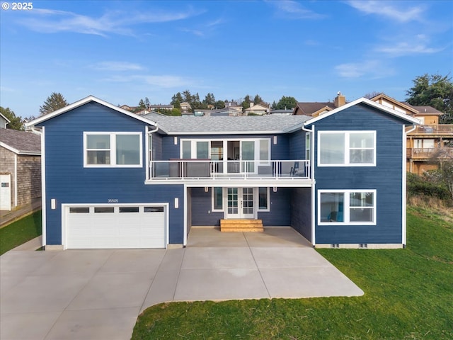 view of front of home featuring a balcony, driveway, a front lawn, french doors, and a garage