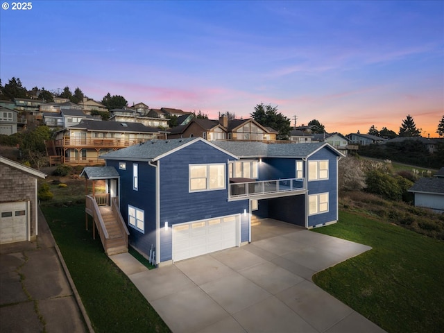 view of front of property featuring a yard, a residential view, concrete driveway, a garage, and a balcony