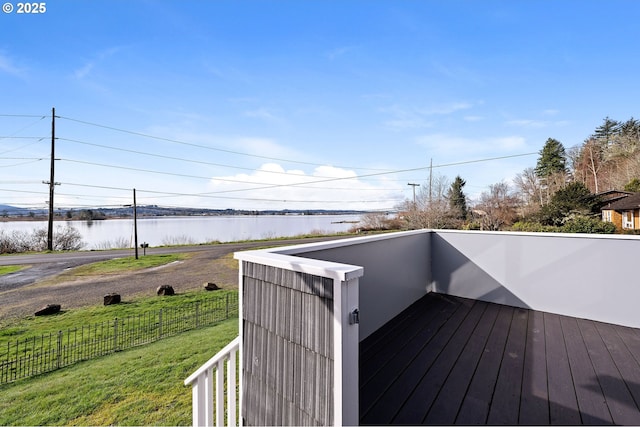 wooden deck featuring fence, a water view, and a lawn