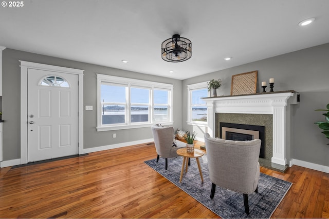 living area with a glass covered fireplace, recessed lighting, wood finished floors, and baseboards