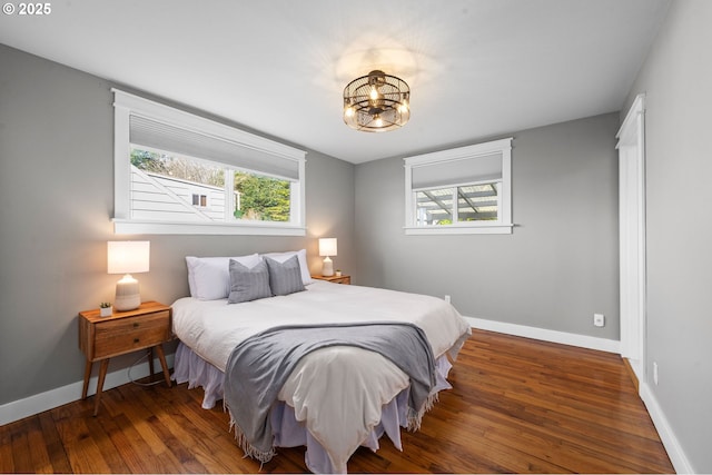 bedroom featuring multiple windows, baseboards, and wood finished floors