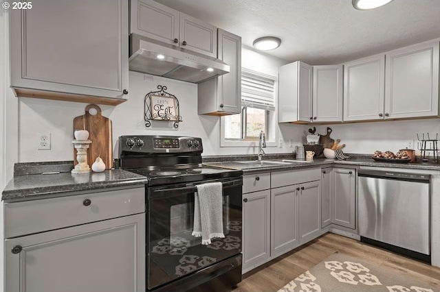 kitchen featuring black / electric stove, gray cabinetry, under cabinet range hood, dishwasher, and light wood finished floors