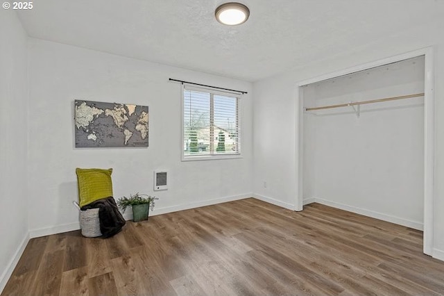 unfurnished bedroom with a textured ceiling, wood finished floors, and baseboards