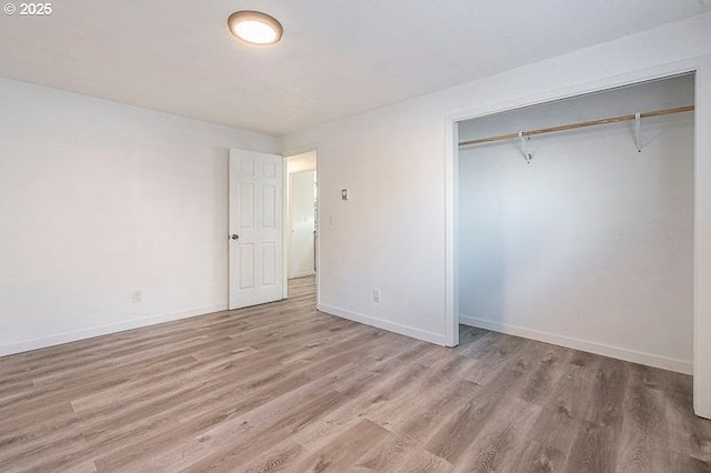 unfurnished bedroom featuring light wood-type flooring, a closet, and baseboards