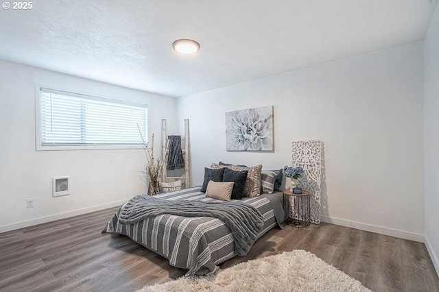 bedroom with a textured ceiling, dark wood-type flooring, and baseboards