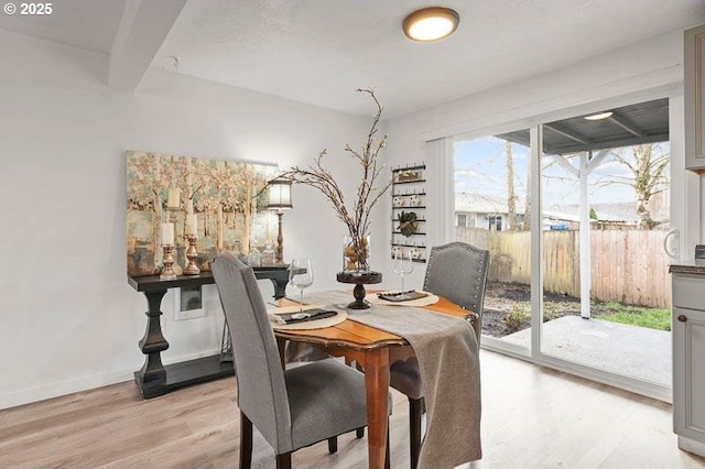 dining space featuring light wood-style floors and baseboards