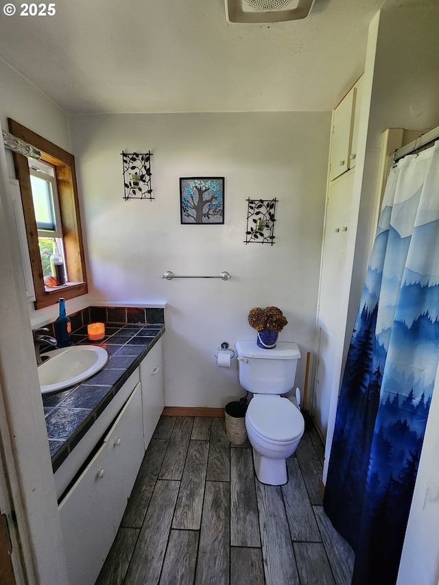 full bath with wood finish floors, toilet, vanity, baseboards, and a shower with shower curtain