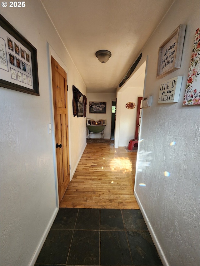 corridor with baseboards and wood finished floors