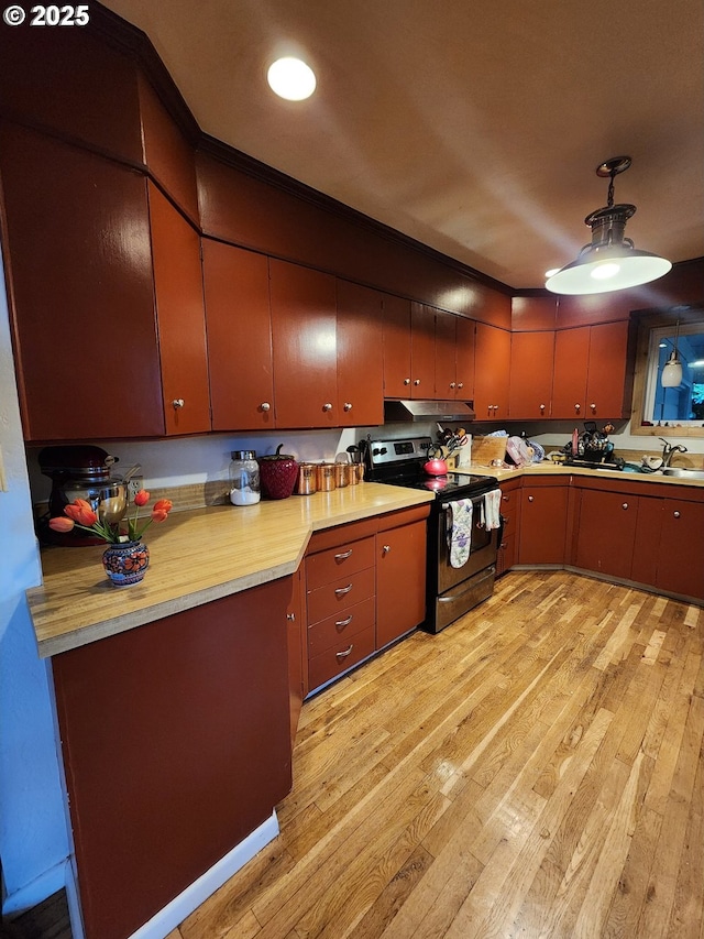 kitchen with stainless steel electric stove, light wood-type flooring, under cabinet range hood, a sink, and light countertops