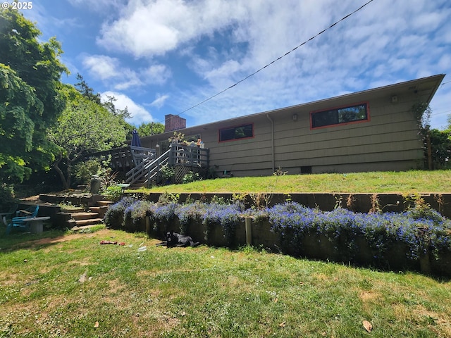 back of property with a lawn, a deck, stairs, and a chimney