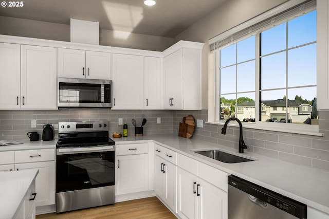 kitchen with stainless steel appliances, sink, white cabinets, and backsplash