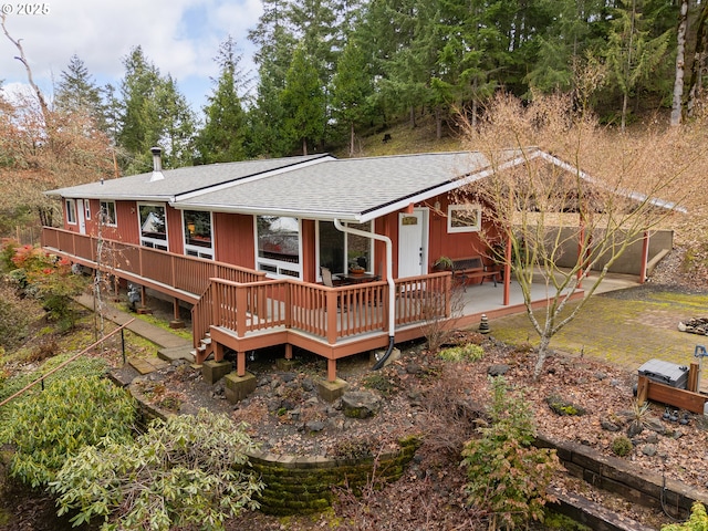 rear view of house with a wooden deck and roof with shingles