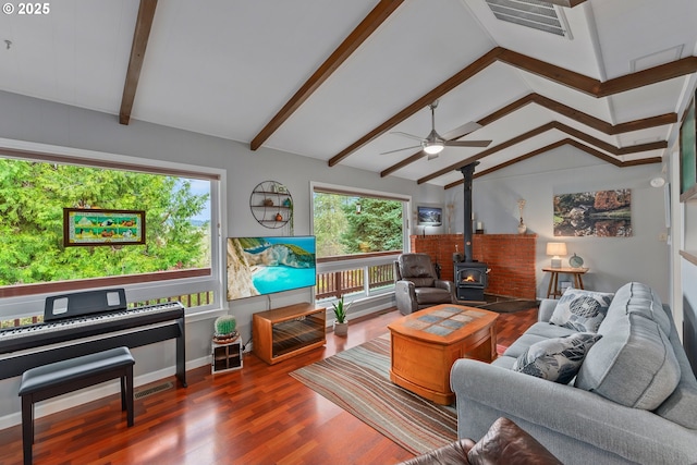 living area featuring a wealth of natural light, lofted ceiling with beams, a wood stove, and wood finished floors