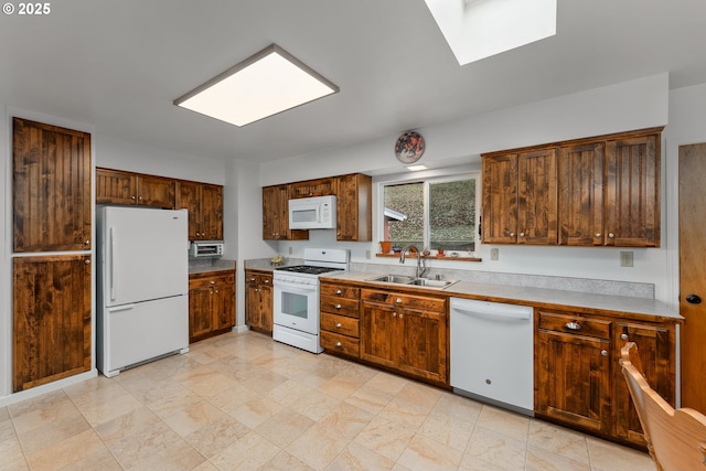 kitchen featuring a sink, white appliances, a skylight, and light countertops