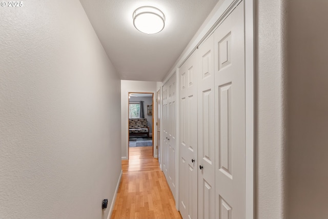 hall with light wood finished floors and baseboards