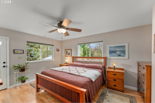 bedroom with multiple windows, baseboards, light wood-type flooring, and ceiling fan