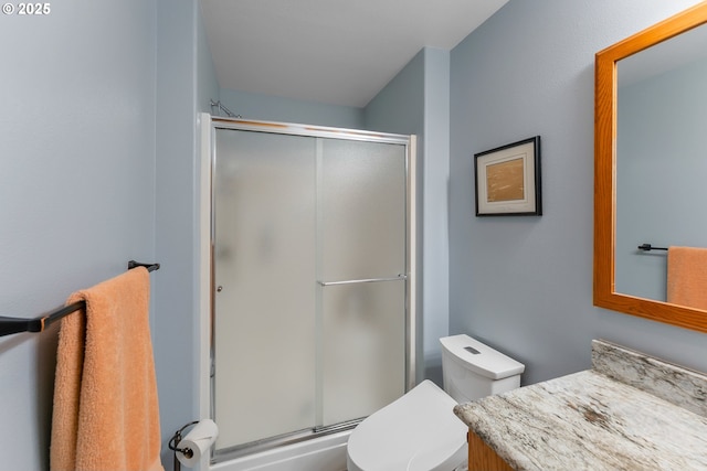 bathroom featuring vanity, a shower stall, and toilet