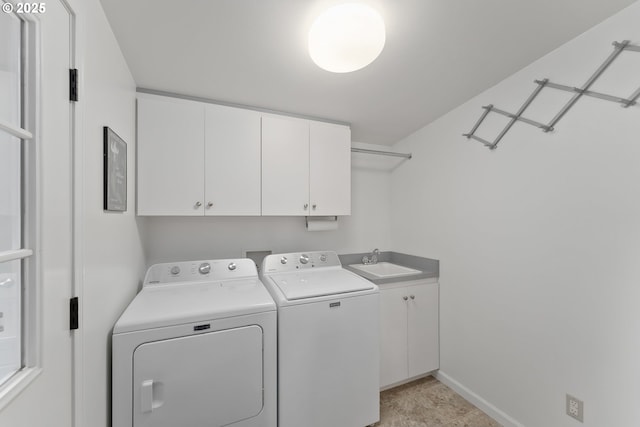 washroom with cabinet space, washer and dryer, baseboards, and a sink