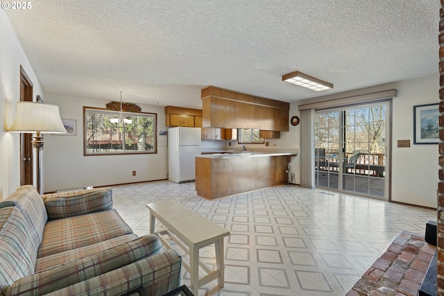 kitchen featuring white refrigerator, decorative light fixtures, a textured ceiling, and kitchen peninsula