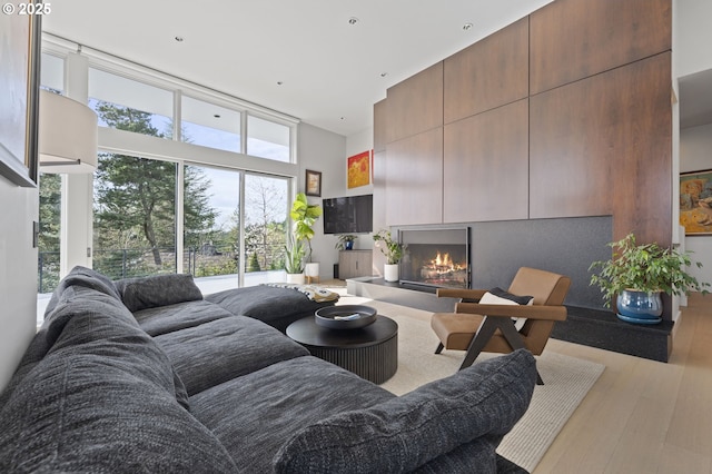 3701 SW 38th Ave, Portland, OR 97221 - living area with a lit fireplace, expansive windows, wood finished floors, and a high ceiling