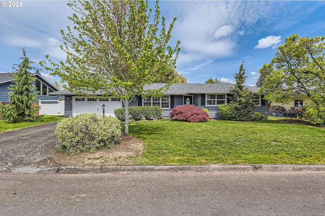 ranch-style home featuring an attached garage, a front lawn, and aphalt driveway