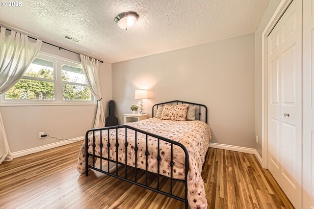 bedroom featuring a closet, baseboards, visible vents, and light wood-type flooring
