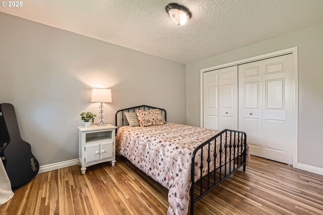 bedroom with baseboards, a textured ceiling, wood finished floors, and a closet