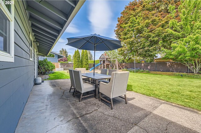 view of patio / terrace featuring a fenced backyard, a playground, and outdoor dining space