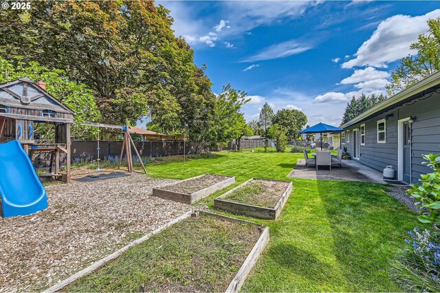 view of yard with a patio, a garden, a fenced backyard, and a playground
